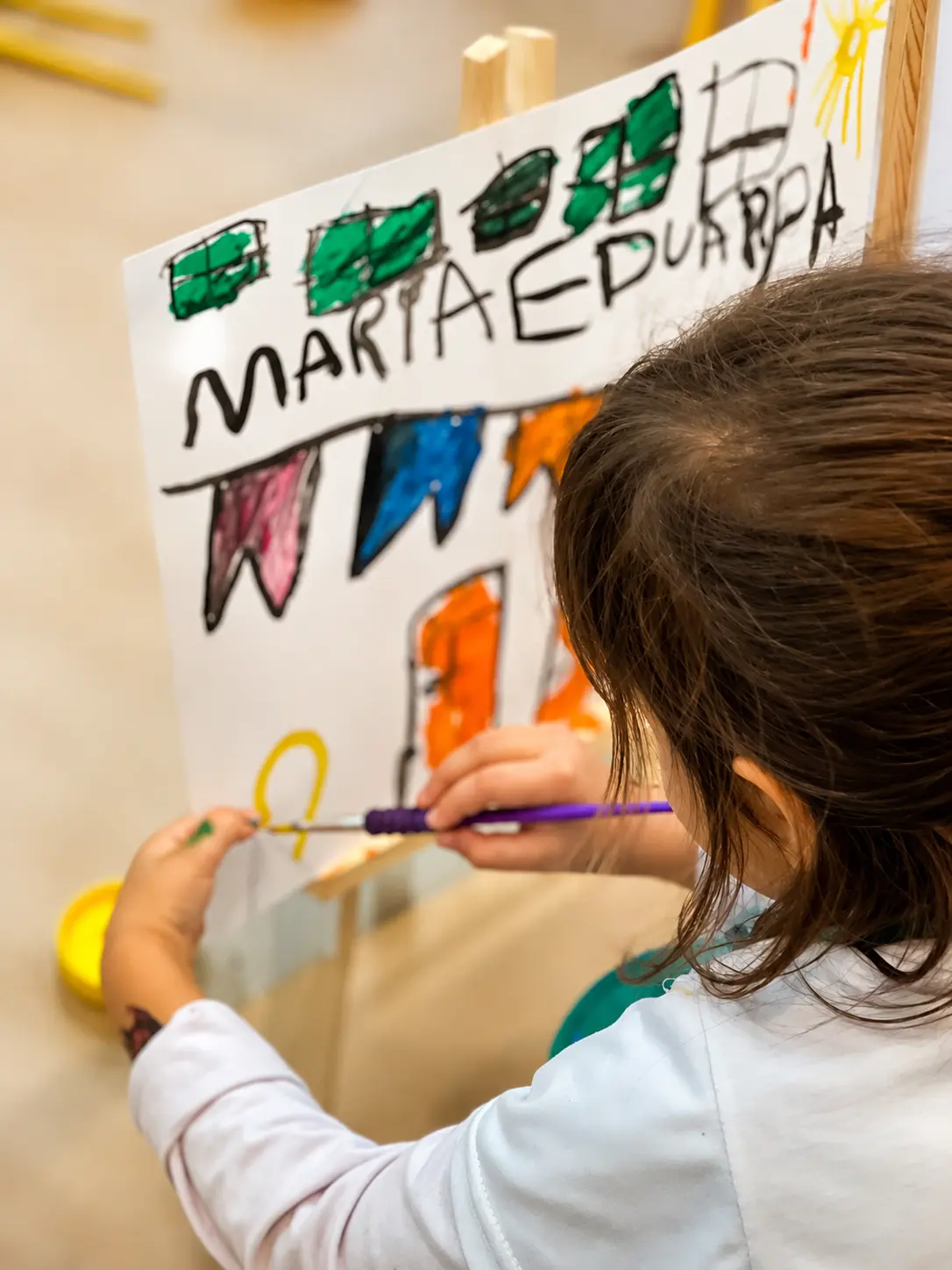 Criança da Educação Infantil Bliss criando uma pintura