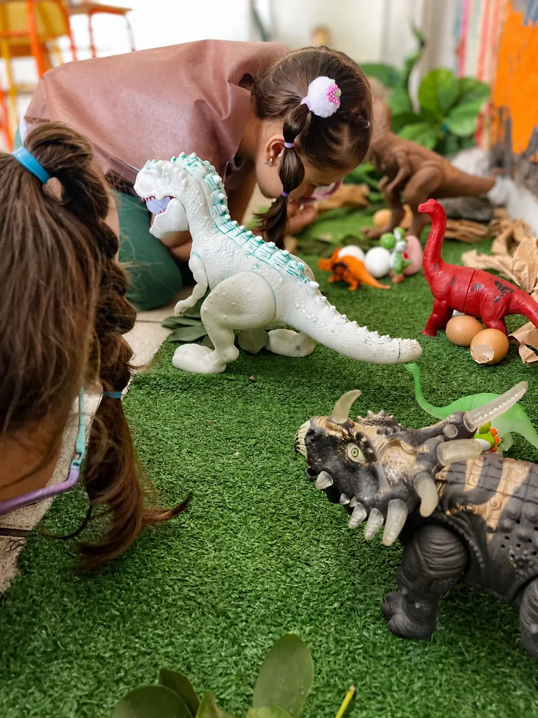 Crianças da Educação Infantil Bliss explorando uma atividade sobre dinossauros