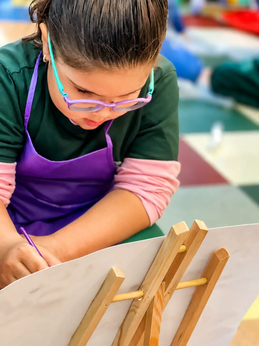 Criança da Educação Infantil Bliss pintando em um cavalete